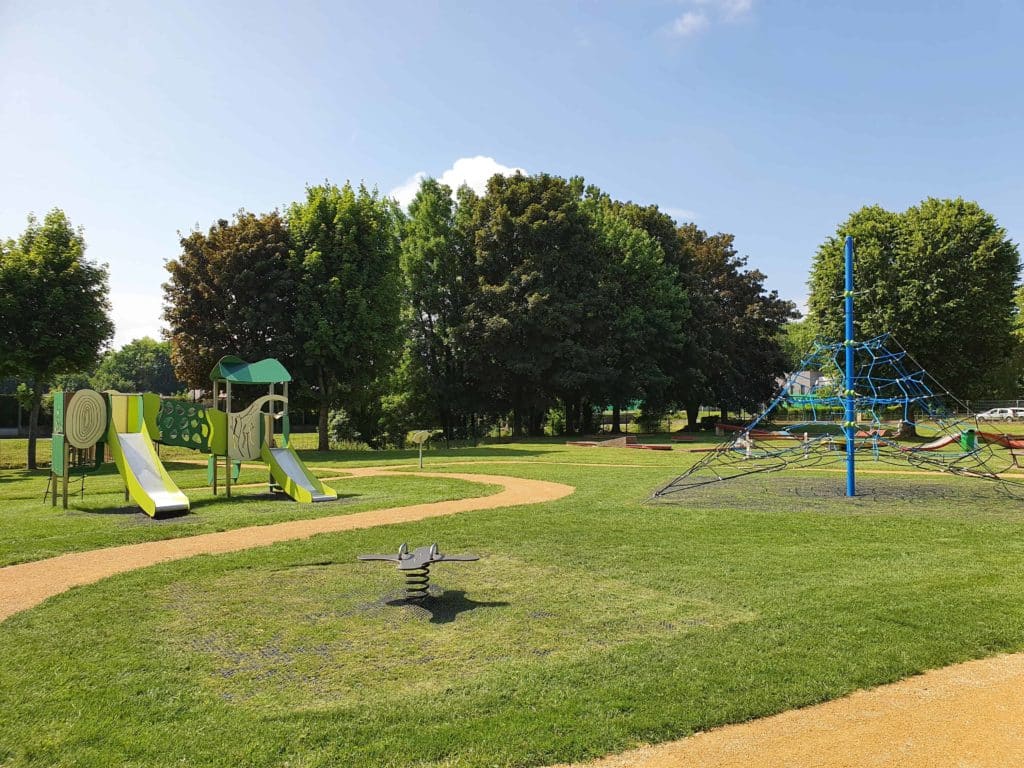 Aire de jeux avec des dalles alvéolaires amortissantes au sol, recouvert de d'herbe naturelle